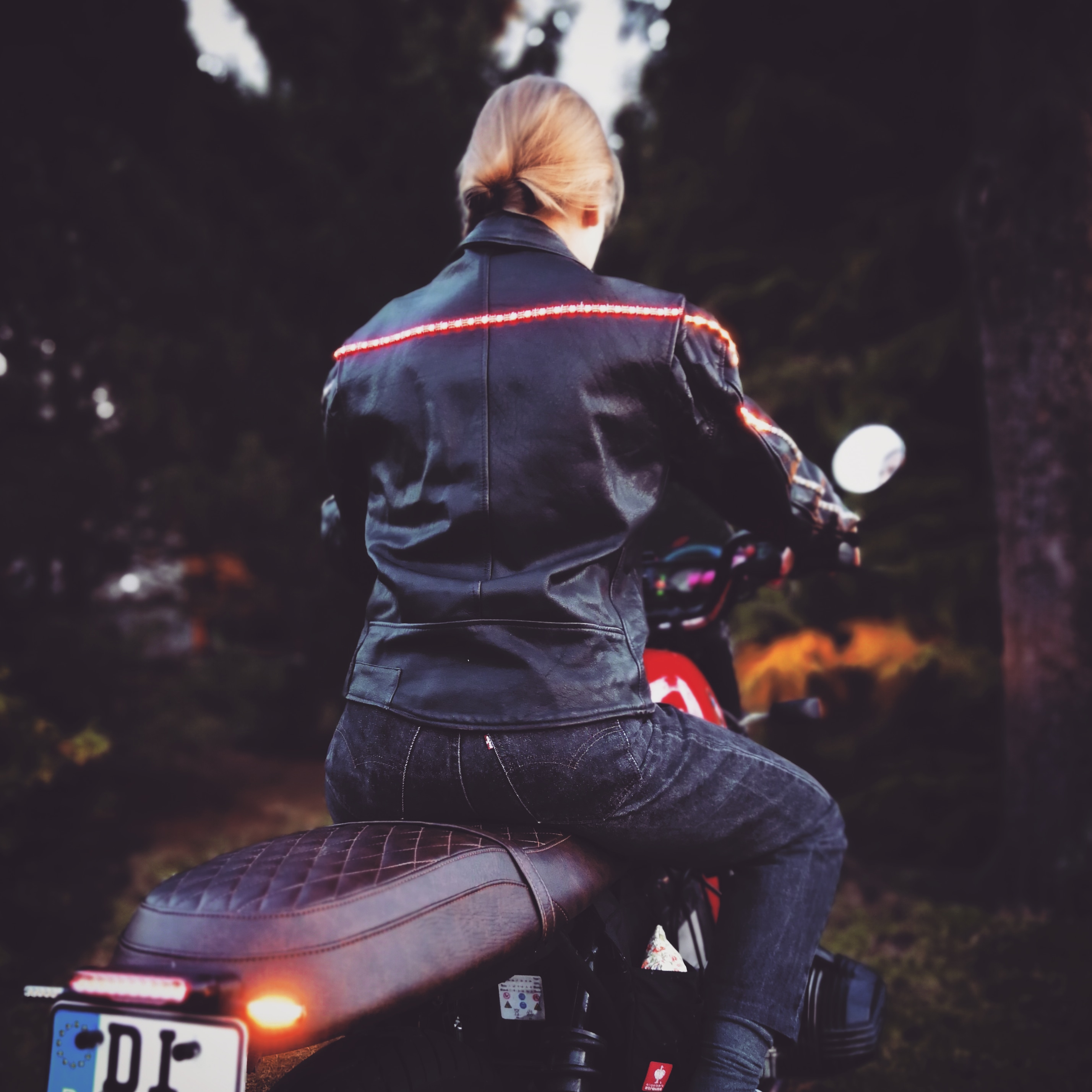 Foto der Motorradjacke von hinten, die von einer jungen Frau auf einem Motorrad getragen wird.